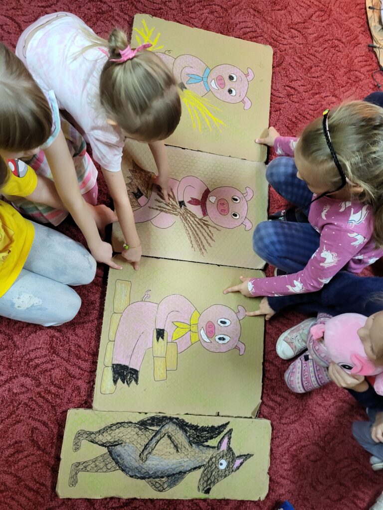 Dzieci oglądają sylwety z bajki ,,Trzy Małe Świnki"